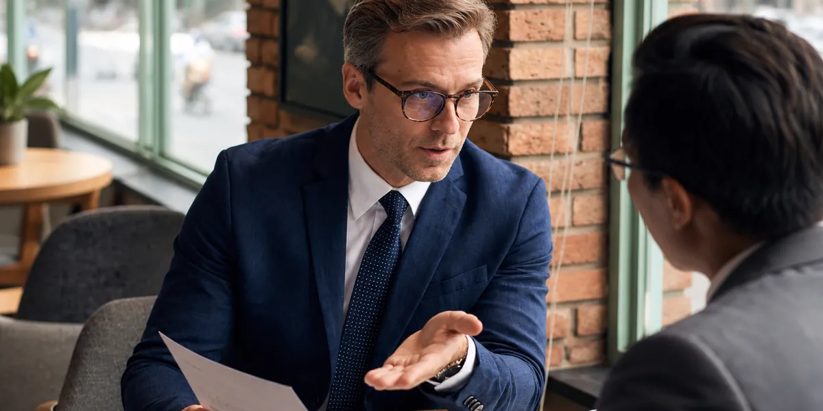 Assessor conversando com o cliente sobre um documento em uma mesa de reunião.